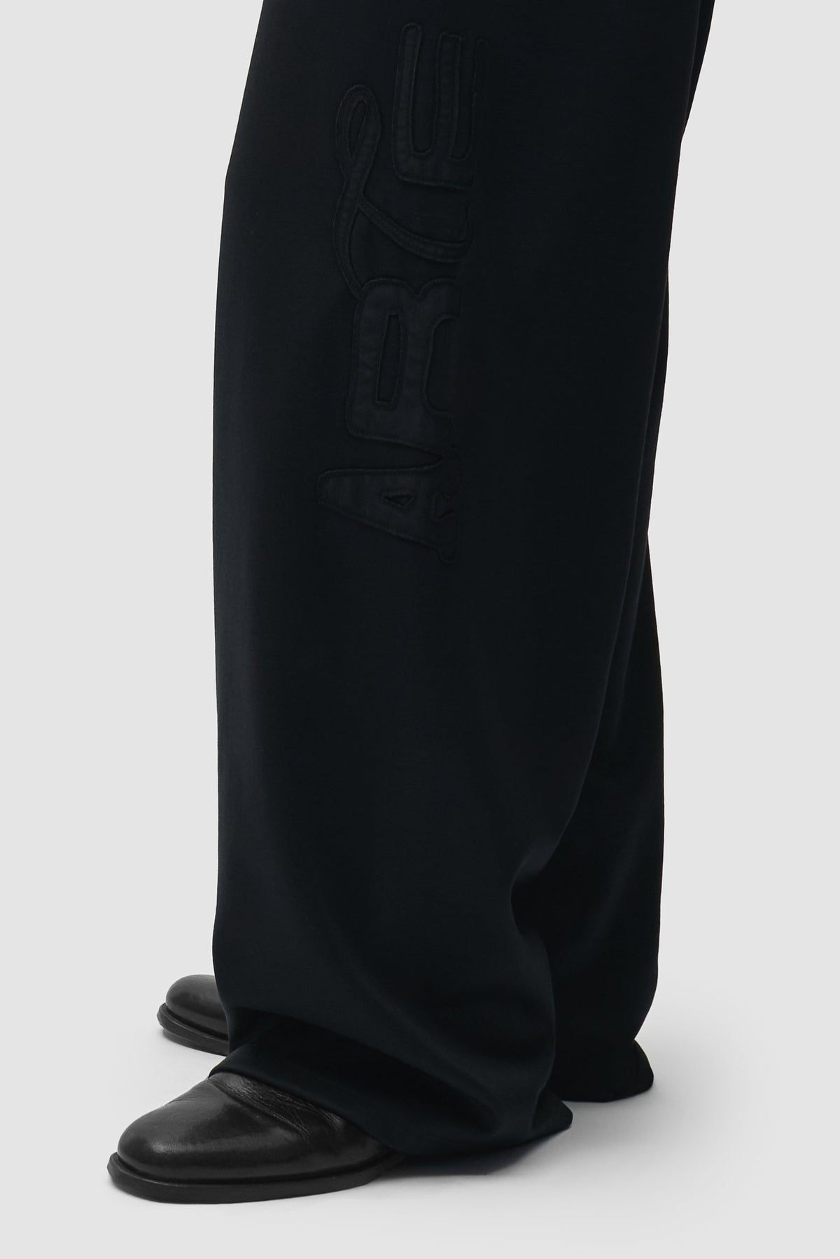Arte Antwerp Polyform Track Pants noires — détail patch logo jambe