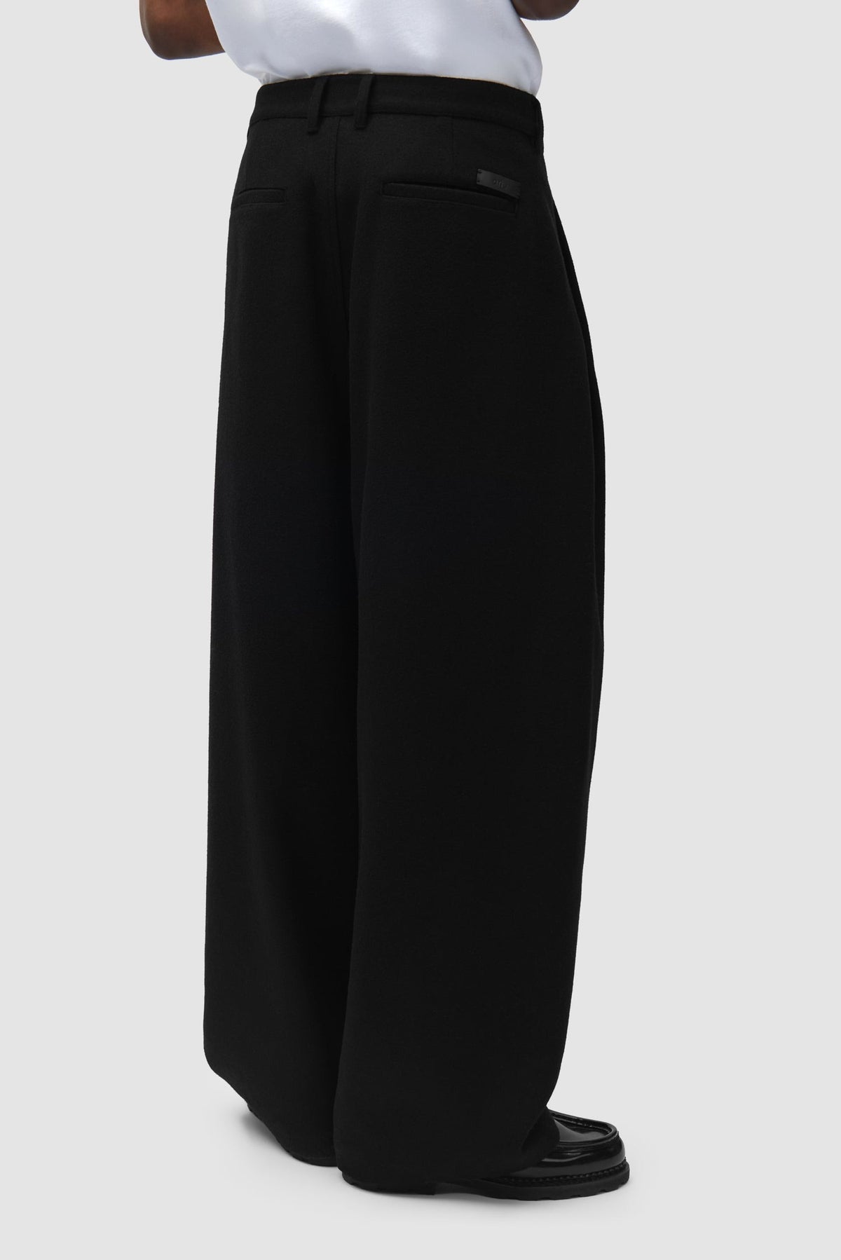 Arte Antwerp Pantalon Wool Pleated Gallery noir – porté de profil, bas du corps