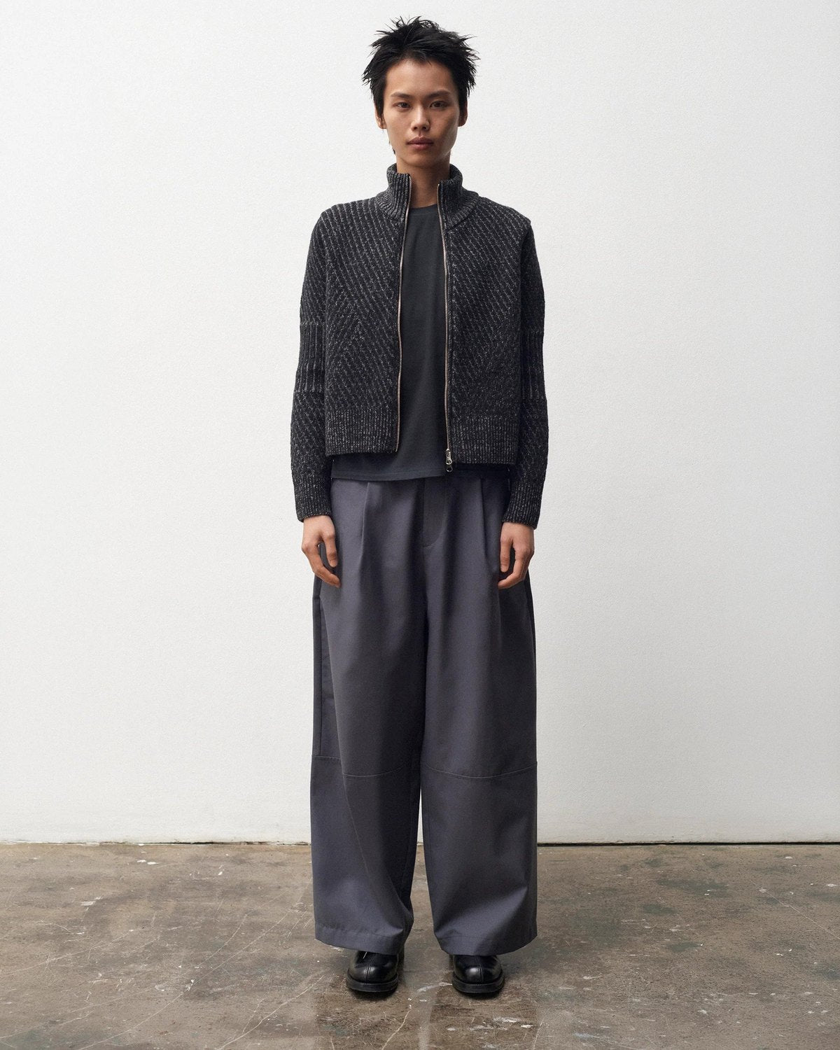 Lookbook YMC AW26, blouson zippé sombre et pantalon large gris