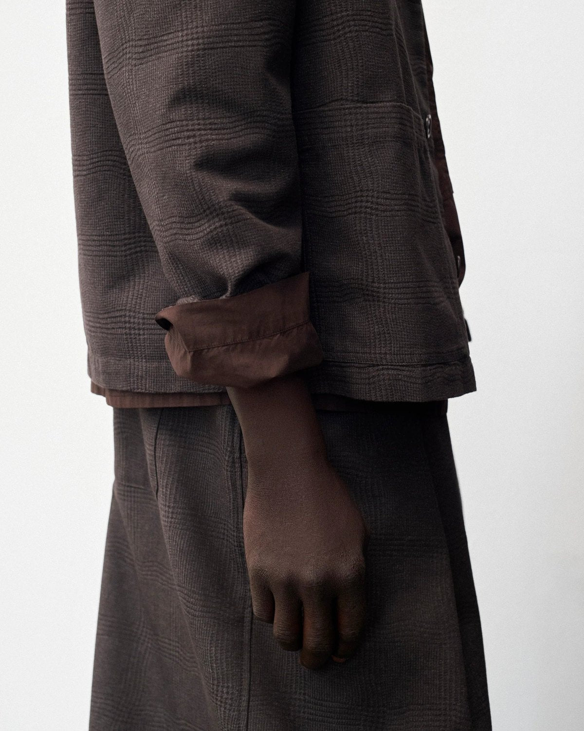 Lookbook YMC AW26, détail de manche et de poche d’un manteau brun